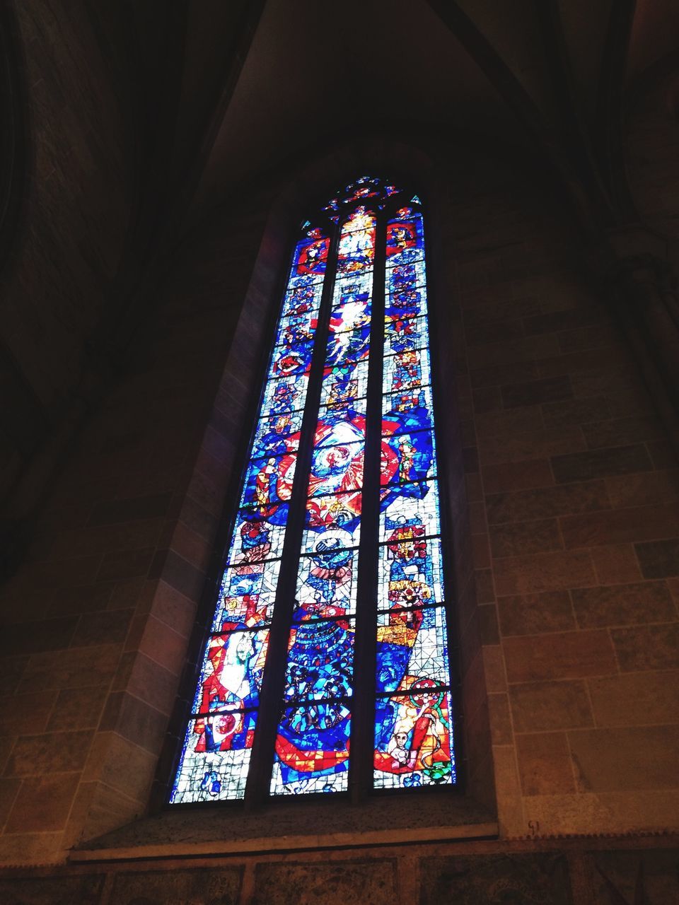 indoors, architecture, built structure, low angle view, window, religion, stained glass, place of worship, church, spirituality, illuminated, glass - material, multi colored, design, pattern, blue, ceiling, decoration, building exterior