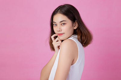 Portrait of beautiful young woman against pink background