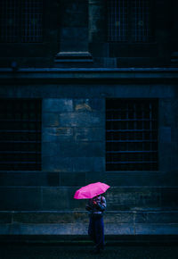 Woman standing on wet umbrella during rainy season