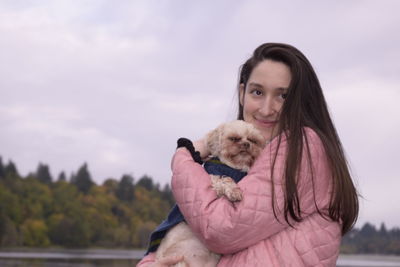 Portrait of woman with dog against sky