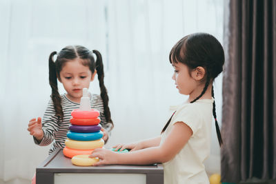 Sisters playing with multi colored toys at home