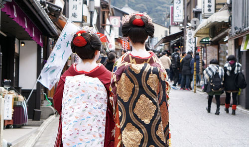 Rear view of women walking on street in city