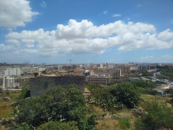 High angle view of city buildings against cloudy sky