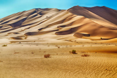 Sand dunes in desert against sky