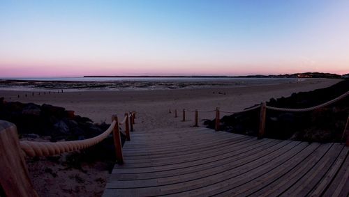 Pier on beach at sunset