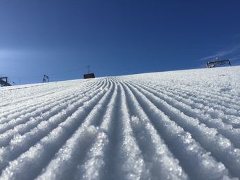 Snow covered field against clear blue sky