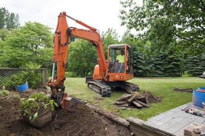 Man in earth mover digging soil at construction site