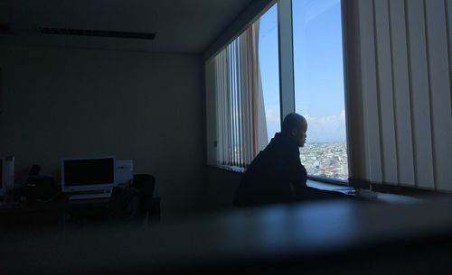 Rear view of man looking through window