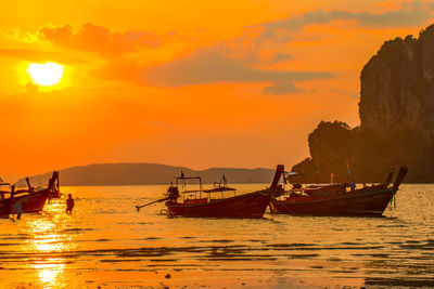 Fishing boats in sea against sky during sunset