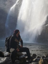 Man sitting on rock by sea