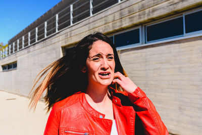 Woman crying while standing against built structure