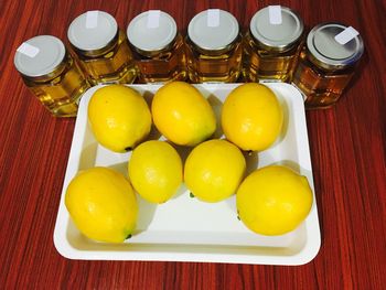 High angle view of bottled honeys and lemons on table