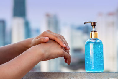 Close-up of hand holding bottle against blurred background