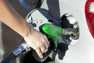 Close-up of hand refueling car on sunny day