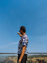 Side view of young woman standing against sky