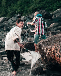 People standing on rock by water