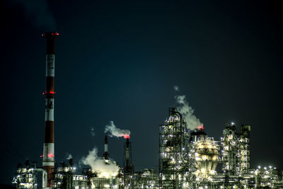 Low angle view of illuminated industry against sky at night