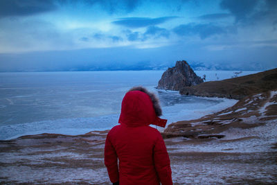 Rear view of person standing at beach against sky during winter