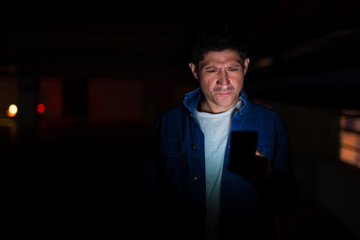 Young man looking away while standing at night