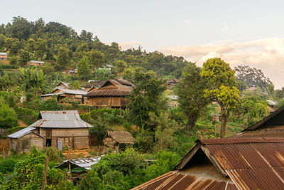 House amidst trees and plants in forest against sky