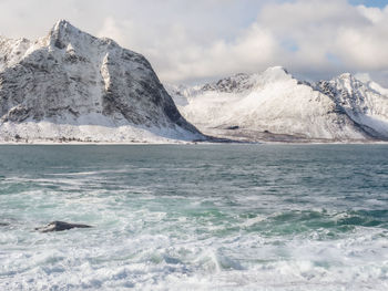 Scenic view of sea and snowcapped mountain against sky