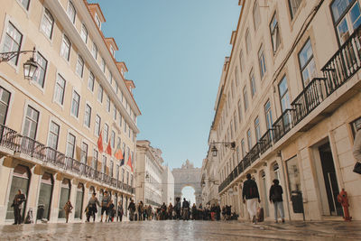 People walking in front of buildings against clear sky