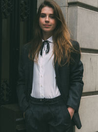 Beautiful young woman standing against wall