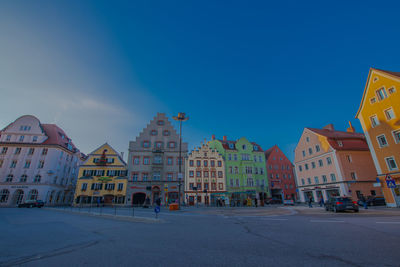 Road by buildings against blue sky