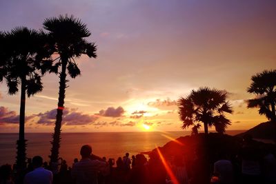 Silhouette palm trees on beach against sky during sunset