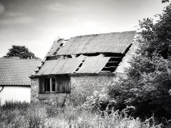 Exterior of abandoned house on field against sky