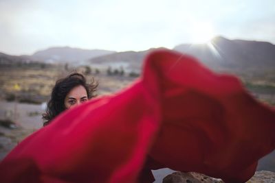 Portrait of woman in red dress against sky