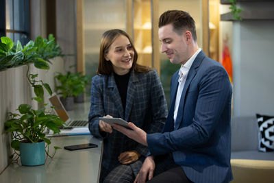 Smiling business people using digital tablet while sitting at cafe