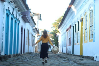 Unidentified tourist with hat in hand walking in the streets of paraty, rio de janeiro, brazil.