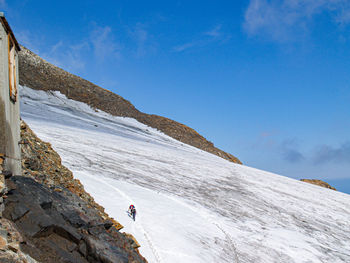 Man on snowcapped mountain against blue sky