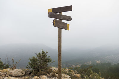 Information sign on wooden post against sky