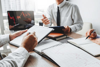 Midsection of man holding paper while sitting on table