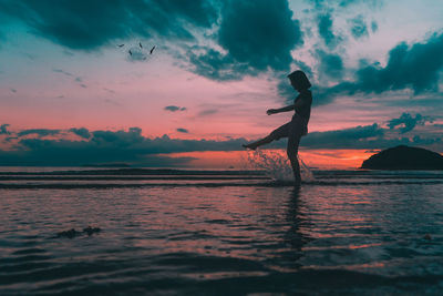 Silhouette person standing on beach against sky during sunset