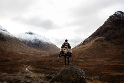 Rear view of man on rock against sky