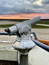 Close-up of metal railing against sky during sunset