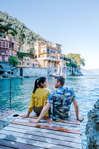 People sitting by sea against sky