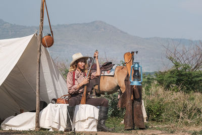 Woman holding gun while sitting outdoors