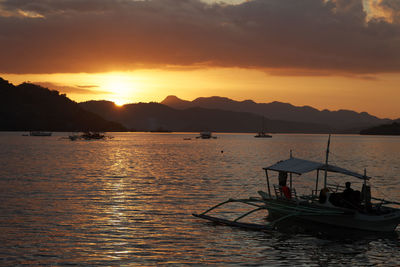 Silhouette sailboats in sea against sky during sunset