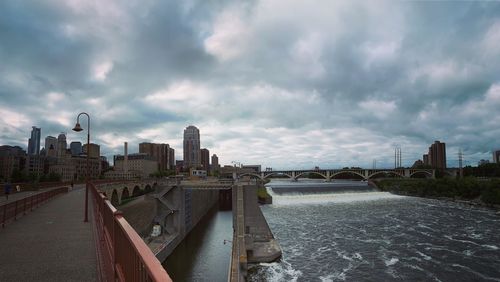 Bridge over river amidst buildings in city against sky