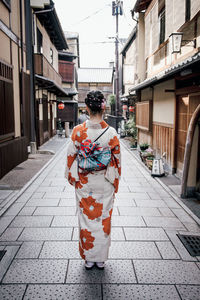 Rear view of woman standing on footpath in city