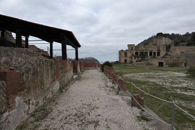 Footpath amidst old buildings against sky