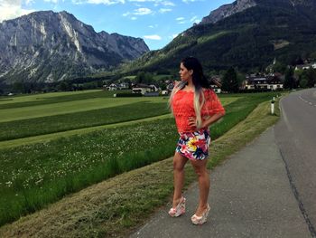 Woman with arms raised on mountain against sky