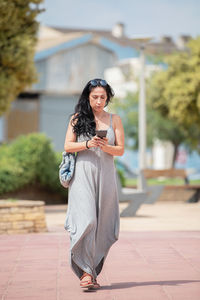 Portrait of young woman standing against buildings