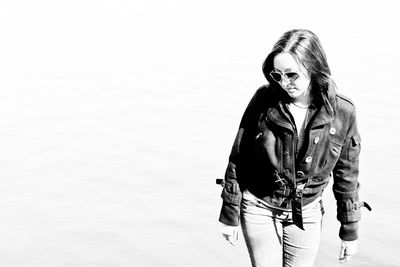 Young woman wearing sunglasses while standing by lake