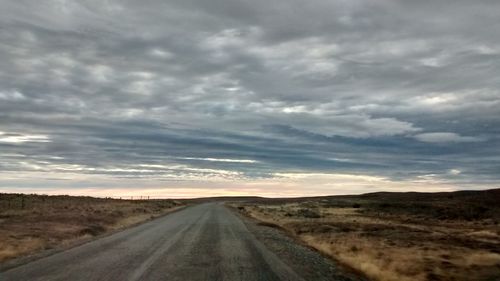 Country road against cloudy sky