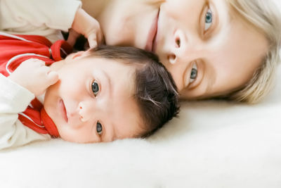 Portrait of mother with cute daughter lying on bed at home